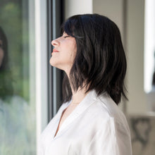 Load image into Gallery viewer, Side view of woman wearing the "Harper" wig, by la Vida. She  is wearing a white robe standing by a window.