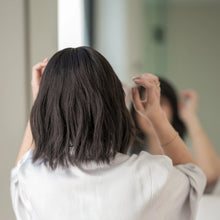 Load image into Gallery viewer, Rear view of woman wearing the "Harper" wig by la Vida. She  is wearing a white robe standing by a mirror.