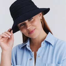 Load image into Gallery viewer, Woman wearing a black hat and light blue shirt against a plain background