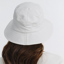 Load image into Gallery viewer, White bucket hat worn by a person with brown hair on a white background